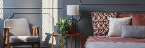 Decorative cushions on bed standing in dark grey room interior w